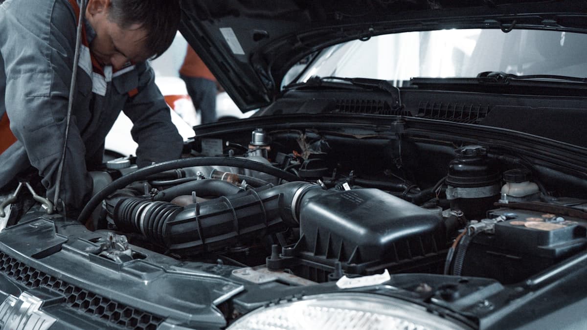 Mechanic performing car repair under the hood — VoiceAI handles calls while your techs wrench