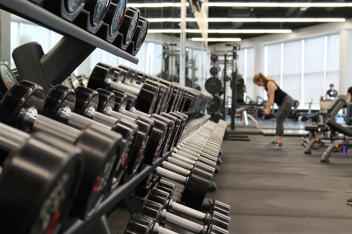 Modern gym floor with weight equipment, cardio machines, and bright lighting