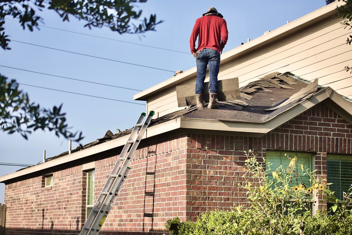 Professional roofer installing shingles on a residential roof during a sunny day